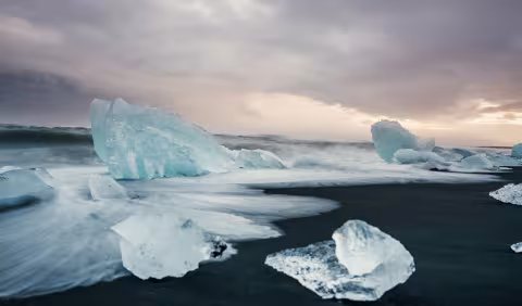 Island: Eisbrocken am Strand in der Dämmerung